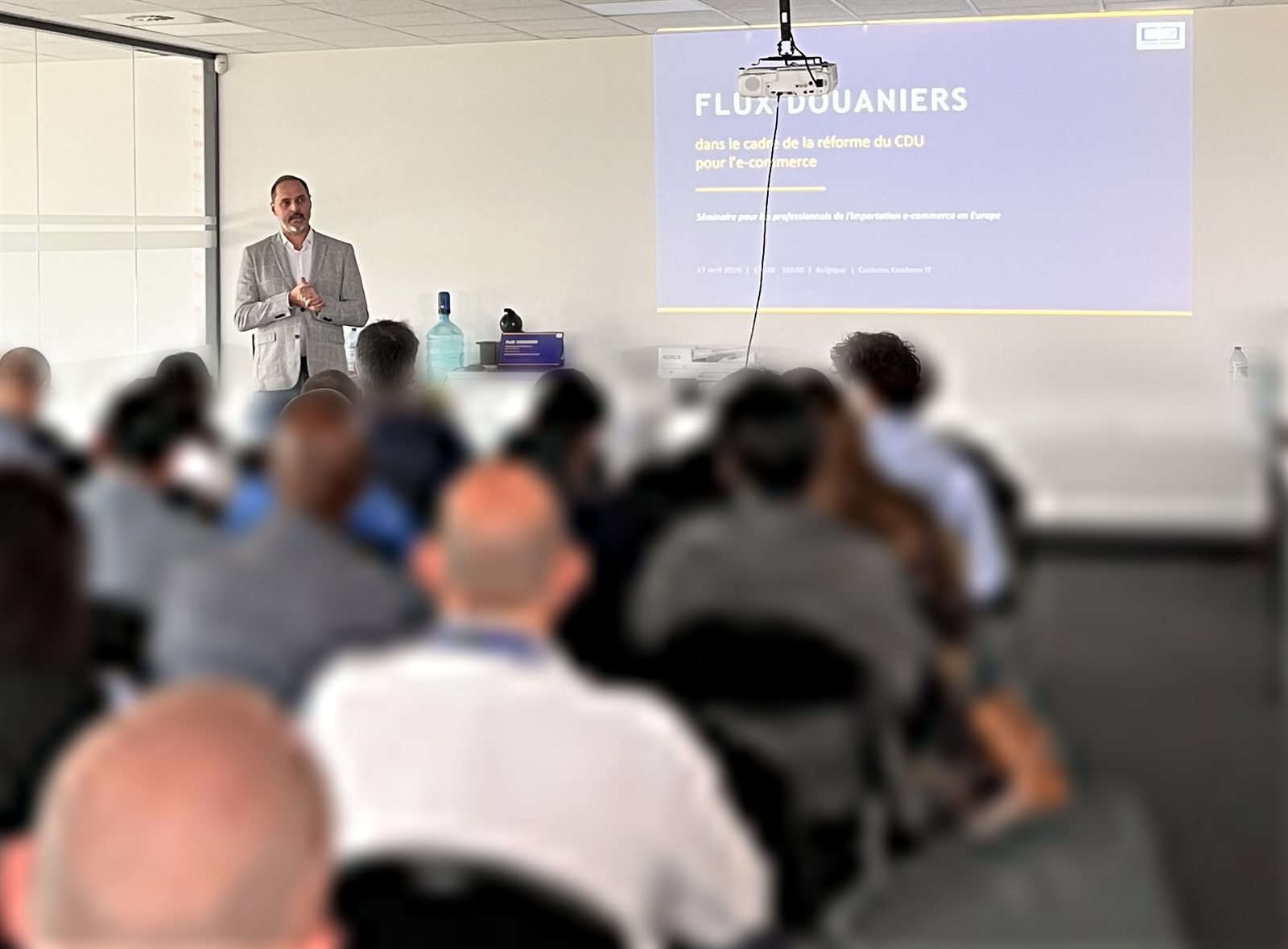 Raphaël Van de Sande, standing in front of the screen, leads the “Customs flows” seminar on the reform of the Union Customs Code for e-commerce.